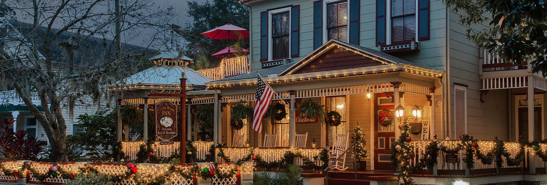 A beautifully decorated Victorian inn adorned with Christmas lights and wreaths.