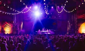 A large crowd enjoys a vibrant live music performance under colorful lights. A large crowd enjoys a vibrant live music performance under colorful lights.