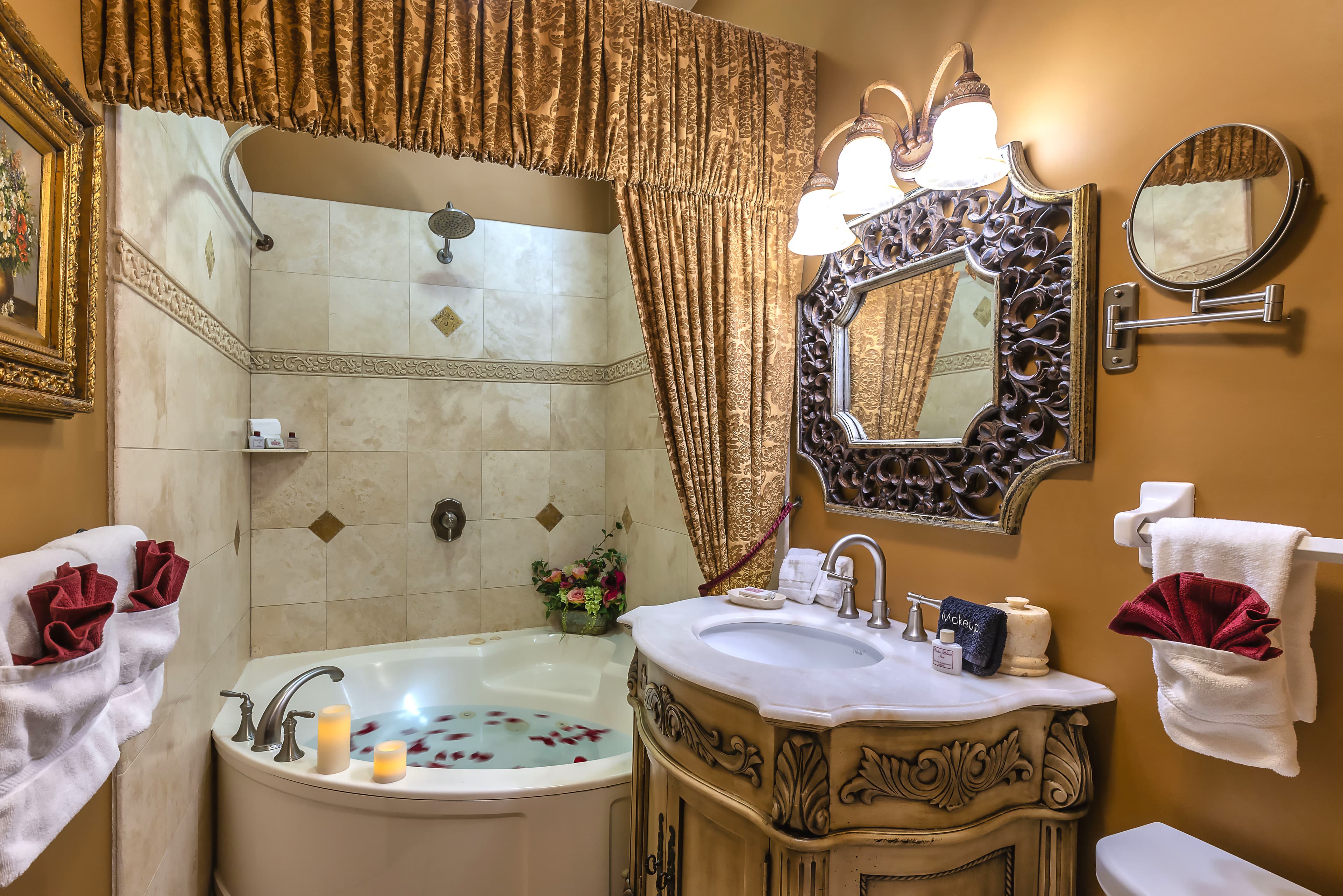 A bathroom with a jacuzzi tub, a sink on a dark wood vanity, and a large mirror with a decorative frame.