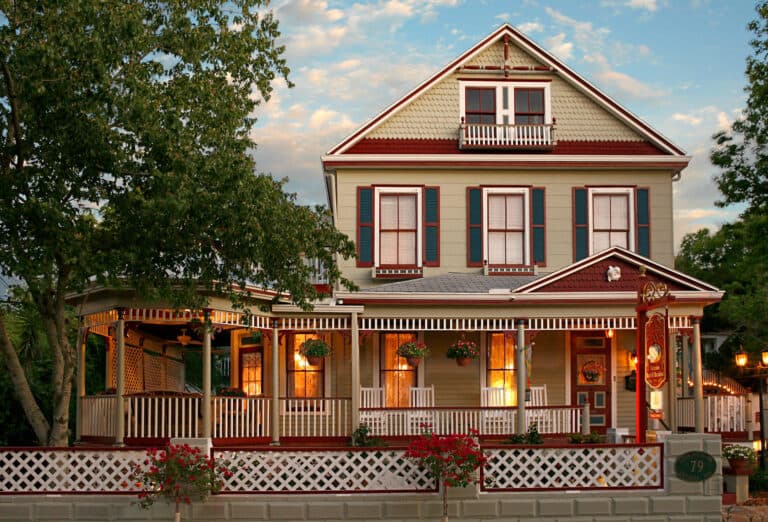 A charming two-story house with a wraparound porch, adorned with flowers and rustic detailing. A charming two-story house with a wraparound porch, adorned with flowers and rustic detailing.