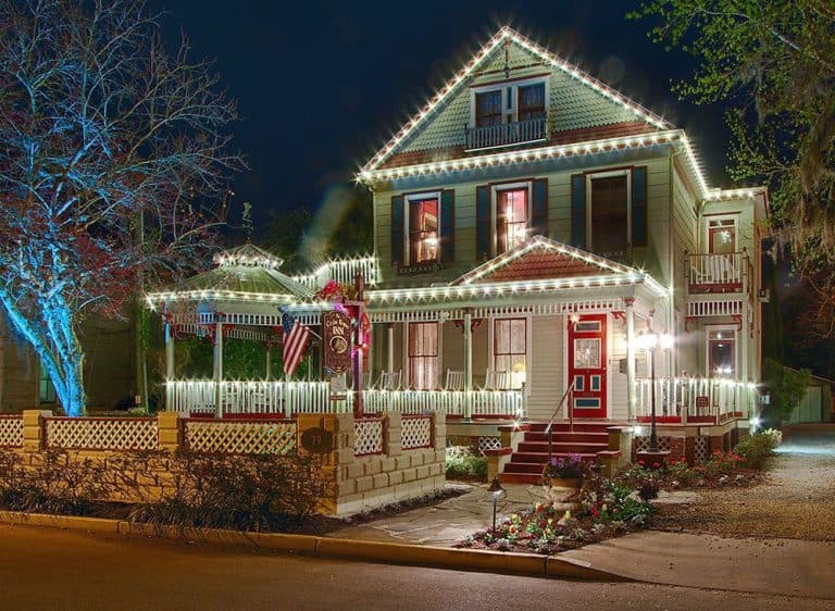 A beautifully lit Victorian house decorated with string lights at night. A beautifully lit Victorian house decorated with string lights at night.