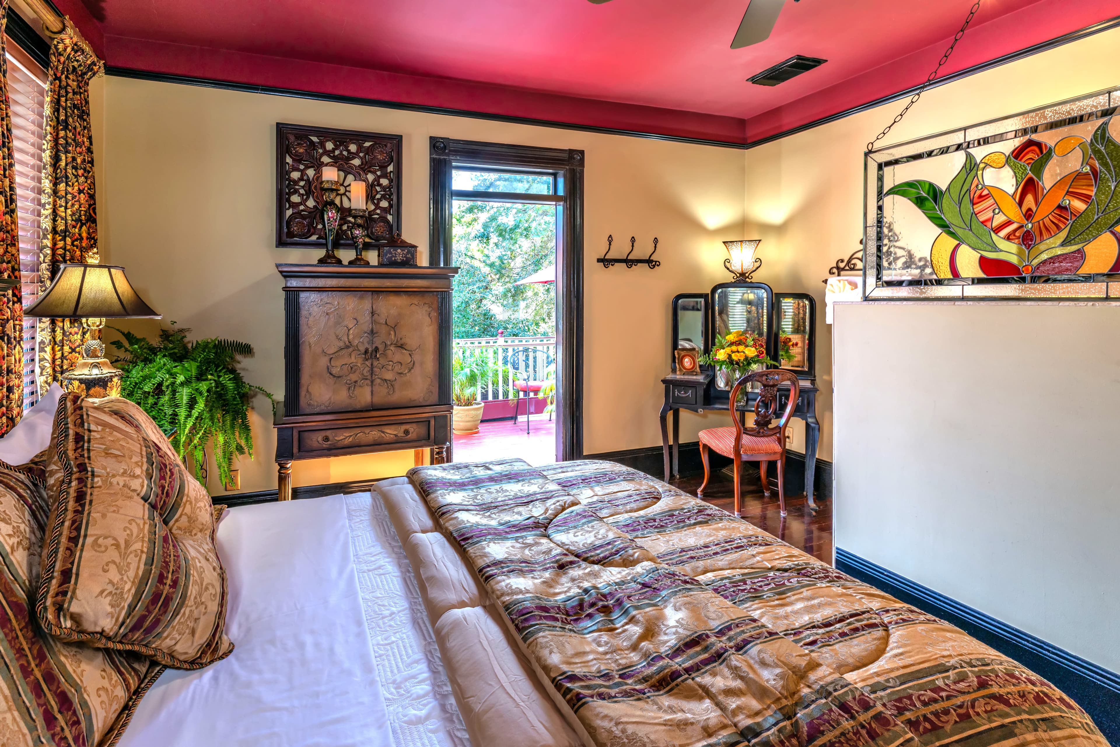 Cozy bedroom with a decorative quilt, stained glass accents, and a doorway leading to a balcony.