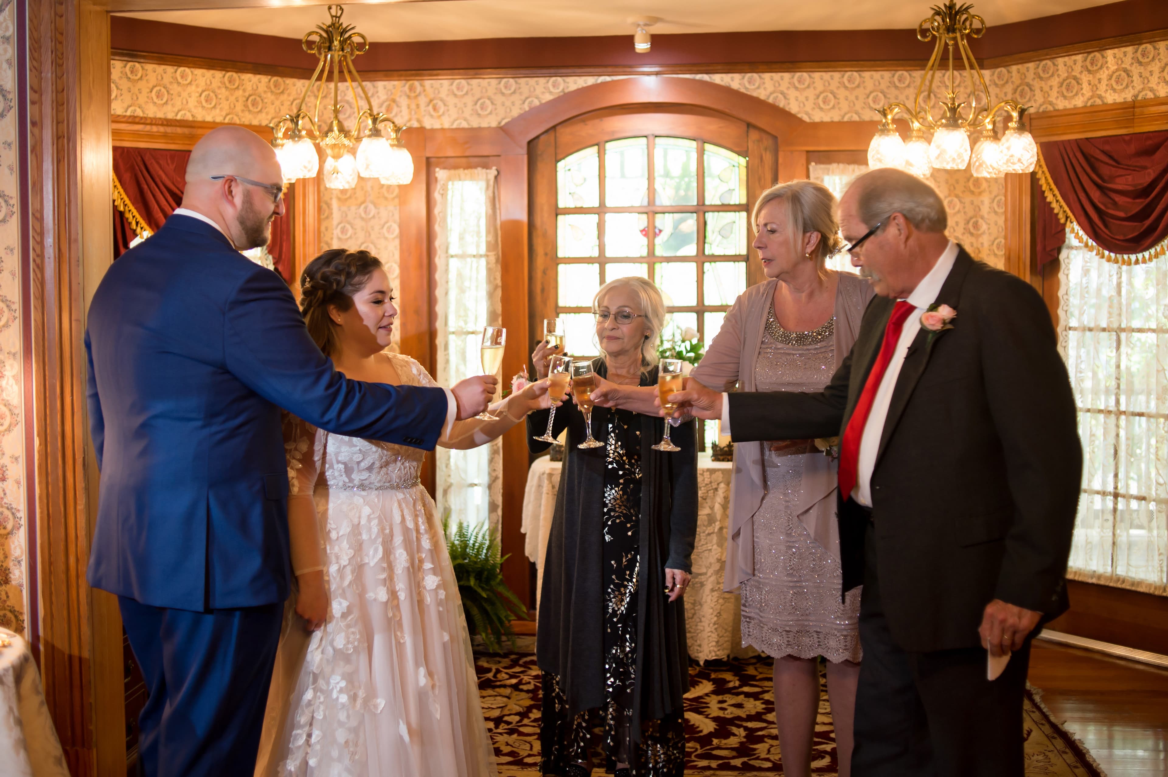 A group of five people toast with champagne glasses in a warmly decorated indoor setting.
