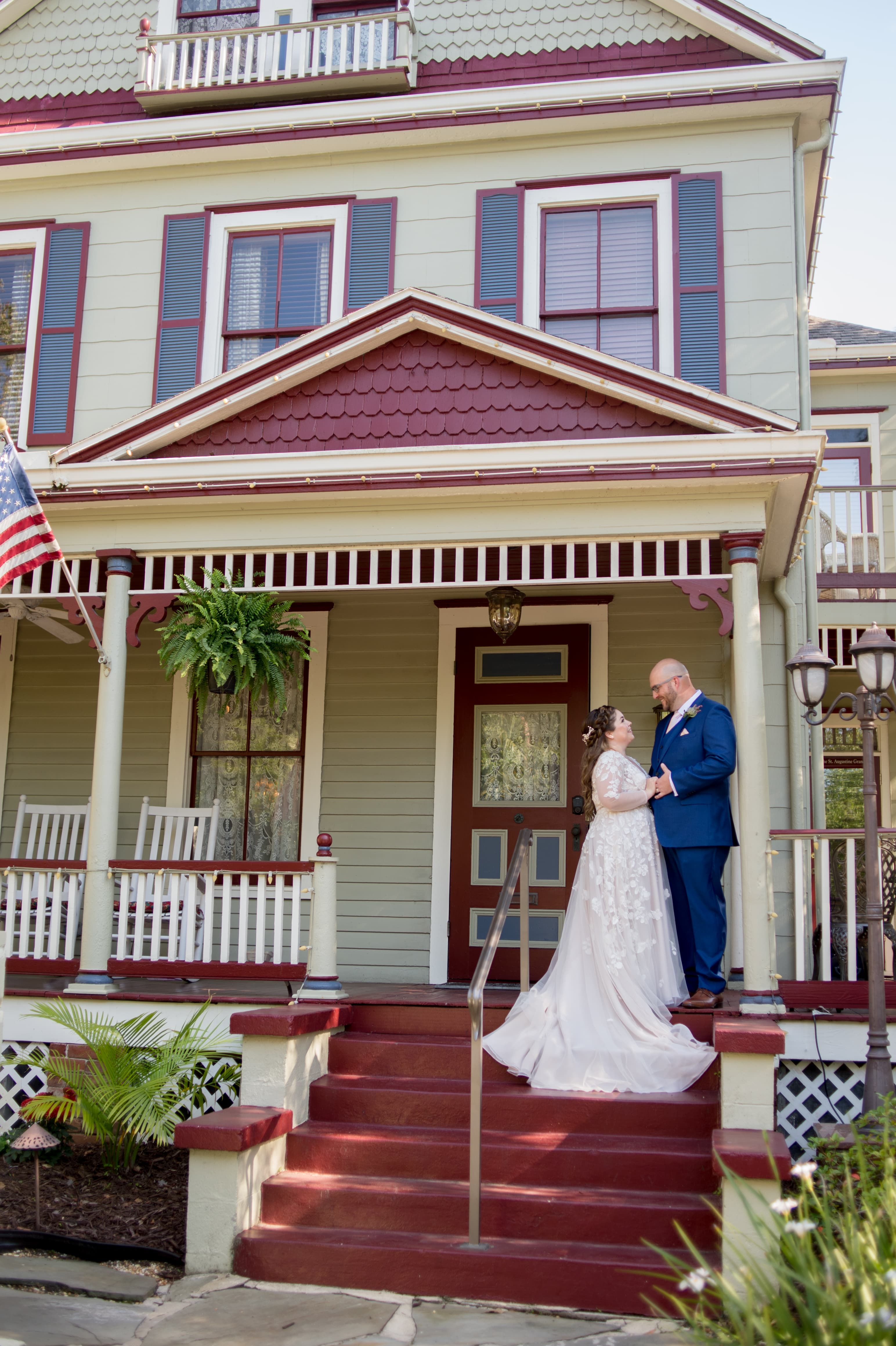 A couple embraces on the steps of a charming, vintage house, exuding love and happiness.