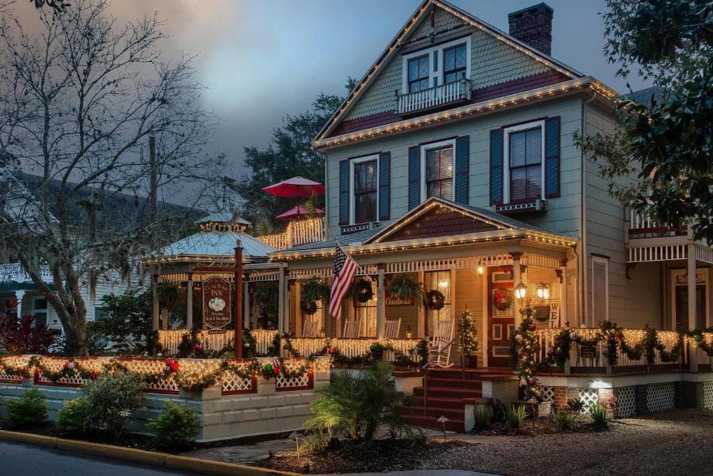 A beautifully decorated historic house adorned with Christmas lights and wreaths.