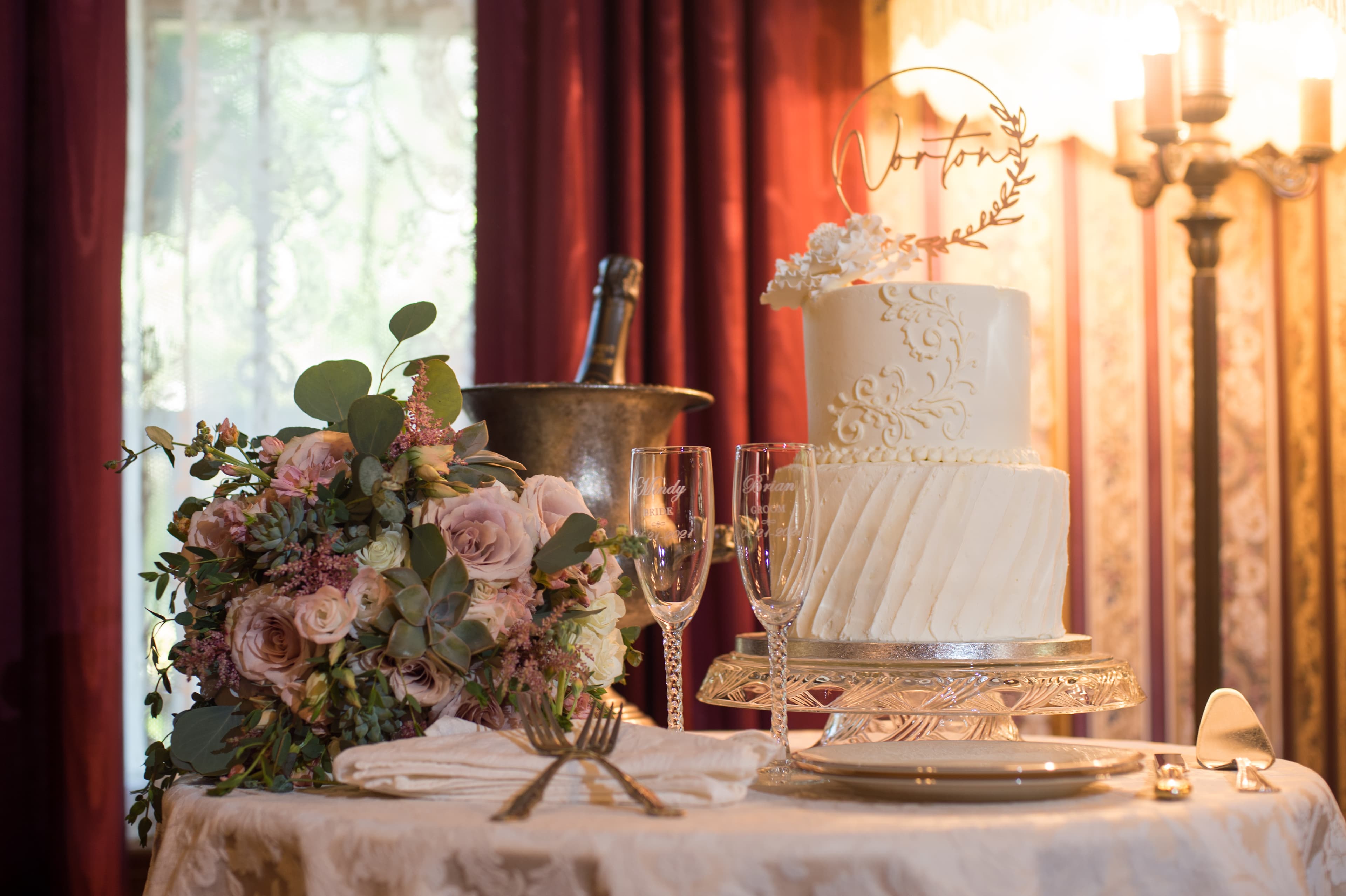 A beautifully arranged wedding cake, floral bouquet, and champagne glasses set on an elegant table.